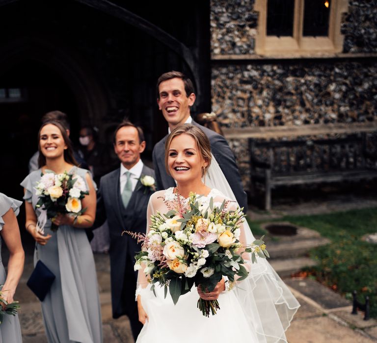 Bride smiles during wedding day holding classic bouquet