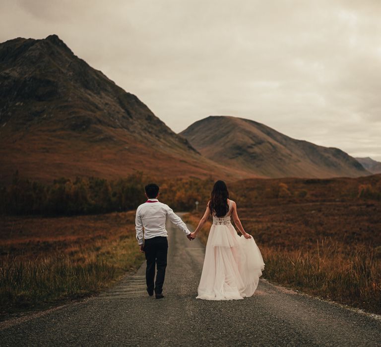 Couple walk down empty road in Scotland 