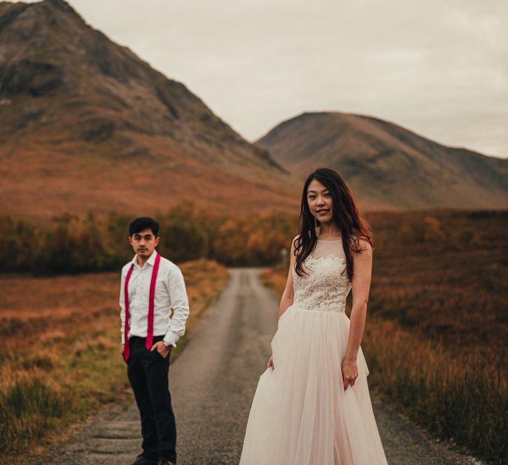 Couple walk on an empty road surrounded by moutains