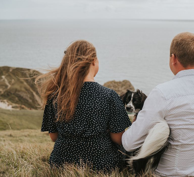 Newly engaged couple sat on the beach in Dorset with their dog for engagement photoshoot 