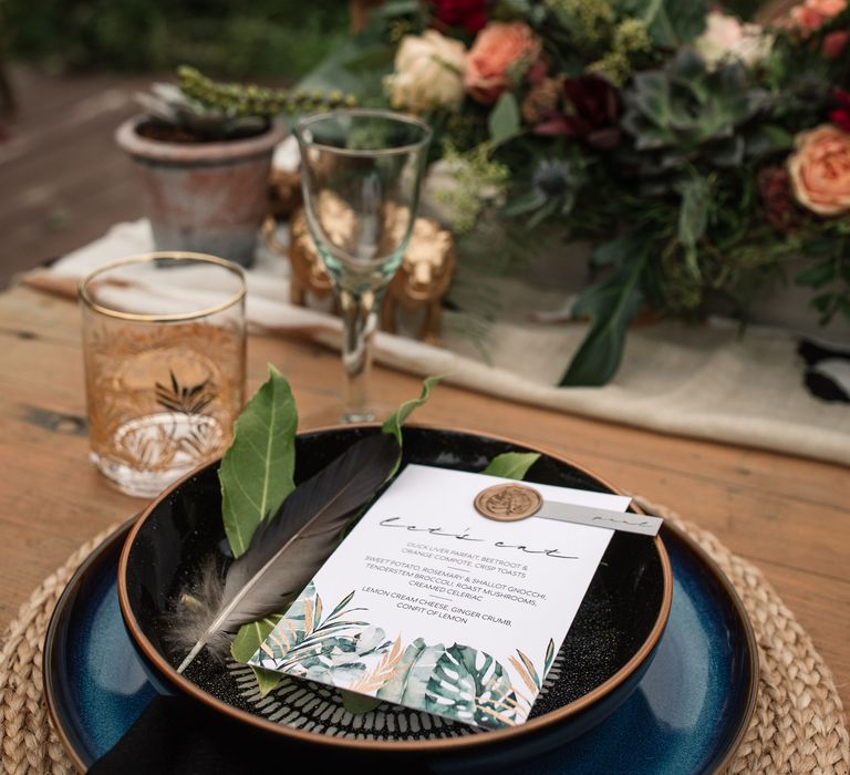 Black plates with floral decor and wedding stationery