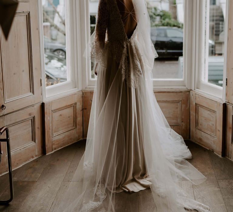 Bride on morning of wedding wearing stunning lace bridal gown with sleeves and open back detail 