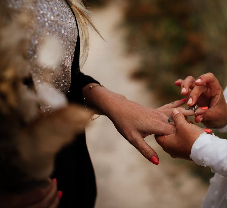 Bride places ring on hand of other bride