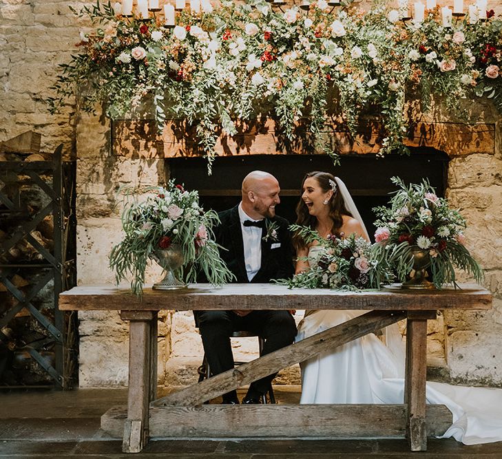 Bride and groom signing the register at Cripps Barn surrounded by natural wedding flowers decor