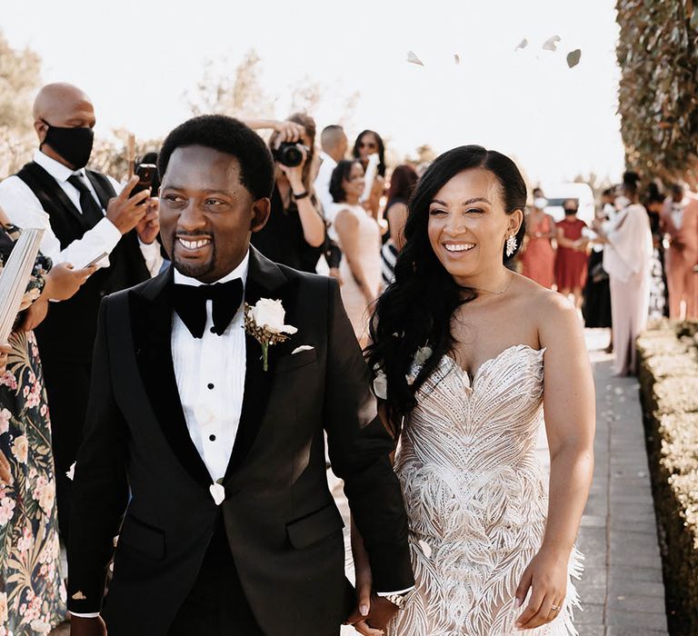 Confetti moment with groom in a tuxedo and bow tie and bride in a sweetheart neckline Biji La Maison de Couture wedding dress with feather detail