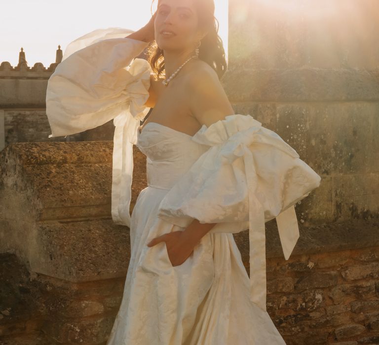 Bride poses in bridal gown with puffed sleeves and pocket in dress