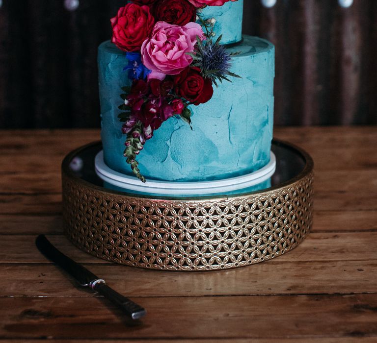 Two tier turquoise wedding cake with pink and red peony decoration