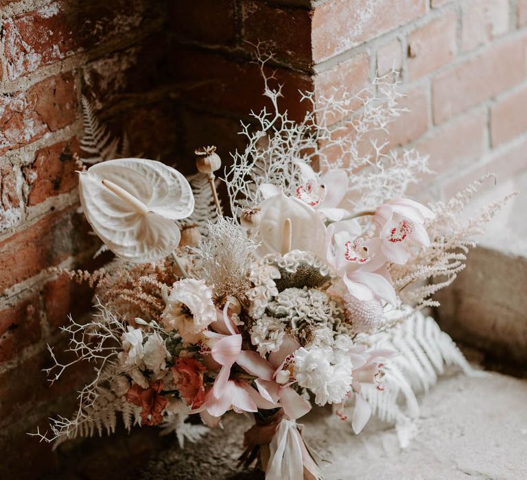 Tropical wedding bouquet with pink and white flowers including chrysanthemums, lilies, anthuriums and white ferns