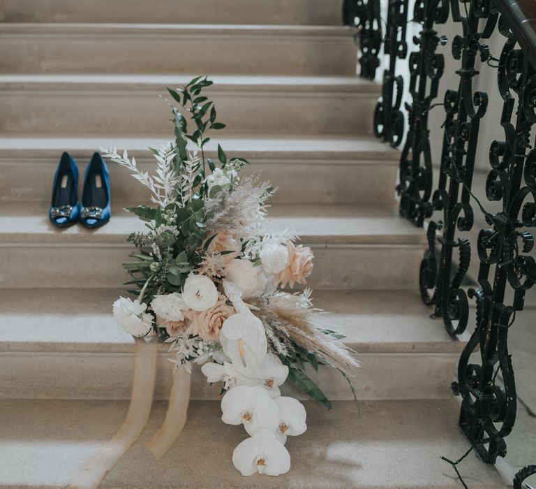 Blue pointed satin Dune heels with square silver buckle and white, pink and green wedding bouquet on stone steps at Came House Dorset Wedding