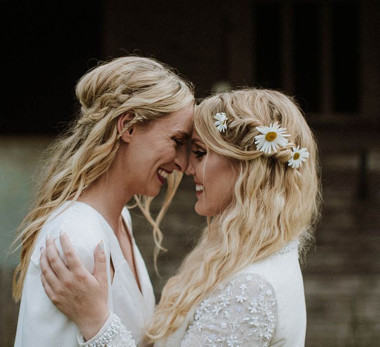 two boho brides with long wavy hair decorated with braids and fresh flowers