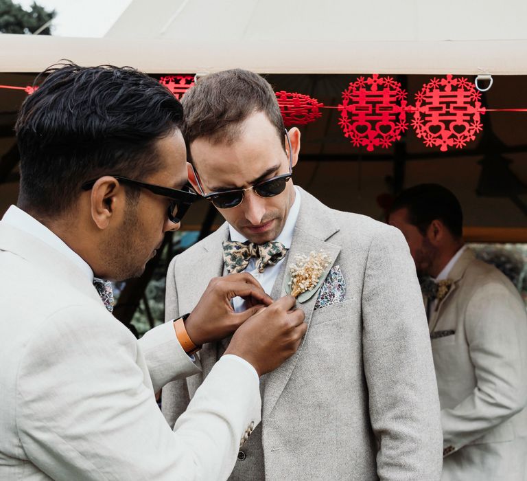 Groom has buttonhole applied by friend on the day of his wedding