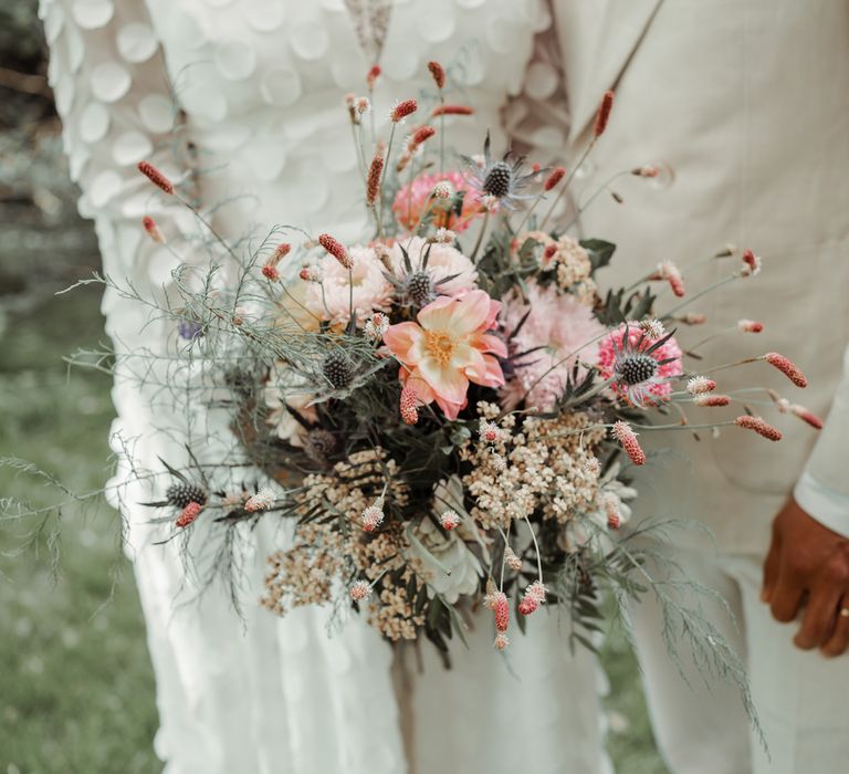 Bride in spotted long sleeve Vagabond wedding dress holds pink, white and green mixed bridal bouquet at Wasing Park wedding