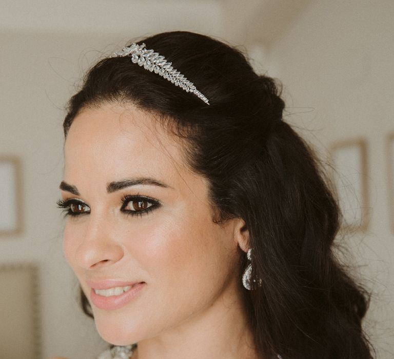 Bride with dark brown hair wearing a silver crown, light pink lipstick and dramatic black eyeliner wedding makeup 