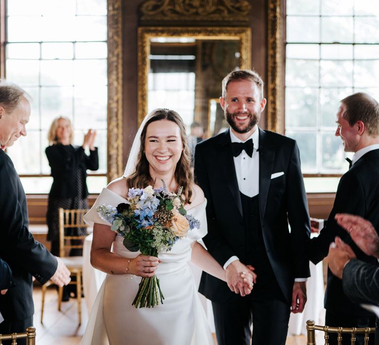 Bride & groom smile as they walk down the aisle on their wedding day