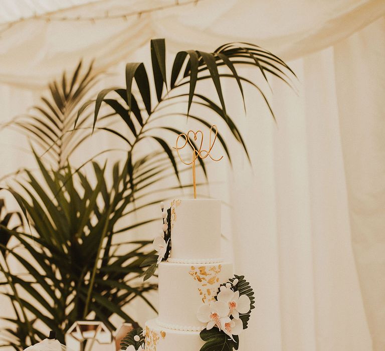 4-tier white wedding cake with tropical inspiration and gold leaf decor