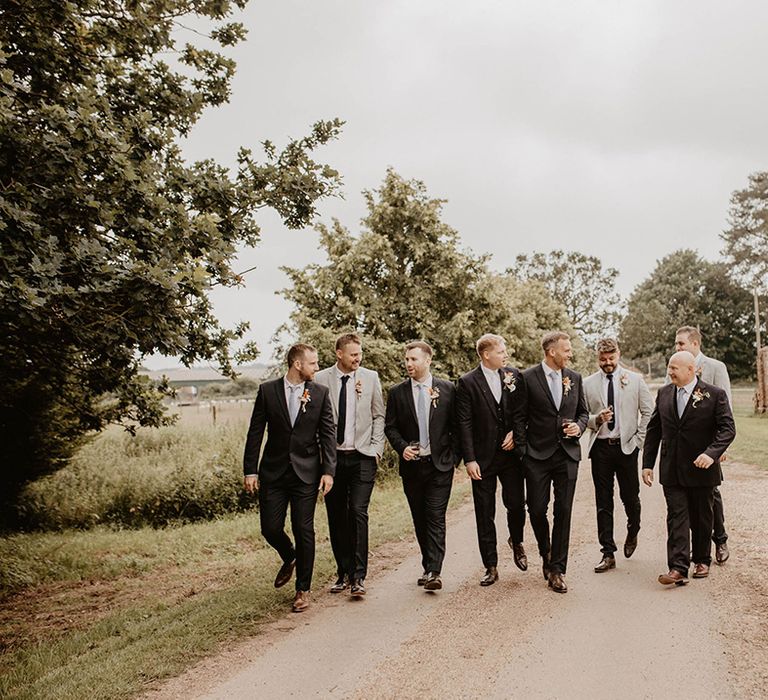 Groom walks with his groomsmen outdoors on wedding day