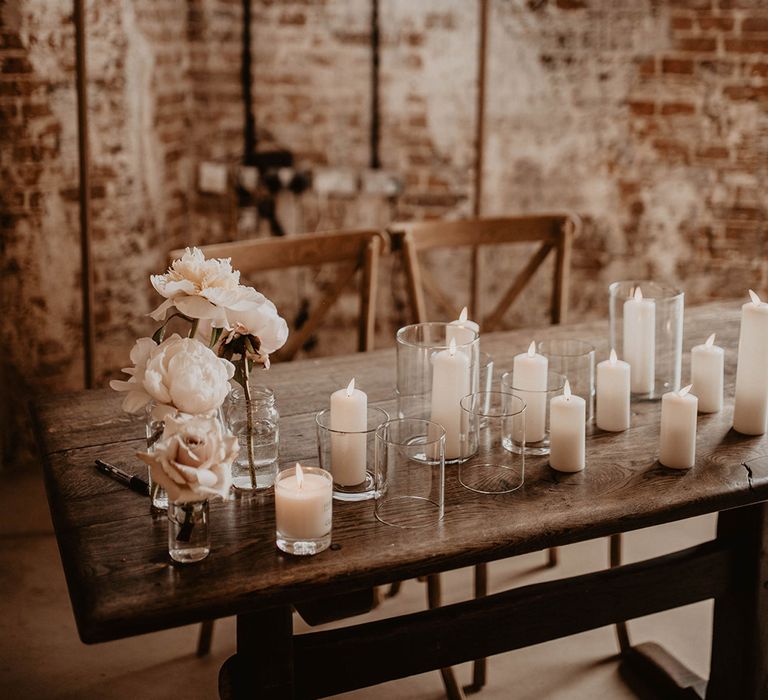 Wooden table complete with white pillar candles, white florals and neon light saying "Till Death Do Us Party"