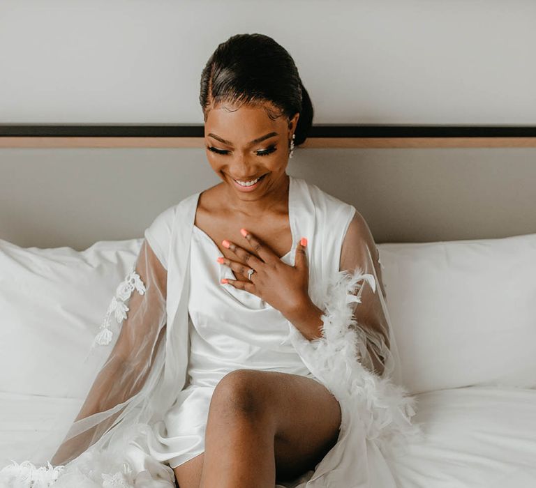 Bride laughs on her wedding day whilst wearing satin white pyjama dress