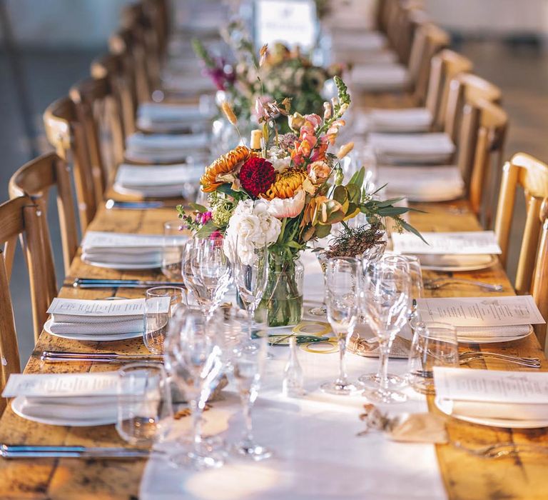 Long wooden tables with colourful wildflower flower centrepieces