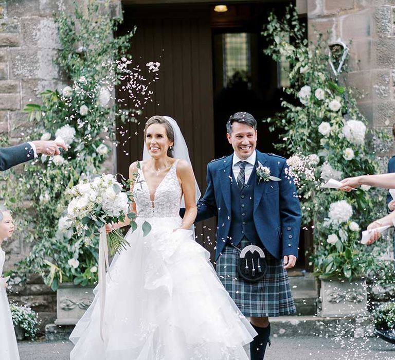 Confetti moment with bride in a princess wedding dress and groom in a tartan kilt 