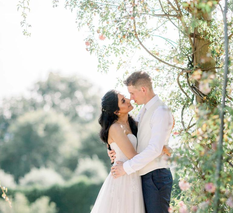 Bride & groom look lovingly at one another outdoors as they embrace on their wedding day