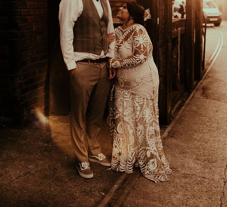 Romantic wedding photograph with boho bride in a lace Rue de Seine wedding dress embracing her groom in wool trousers and a tweed waistcoat 