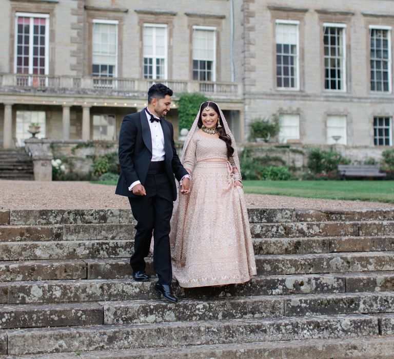 Bride & groom walk down staircase outdoors at Ragley Hall 