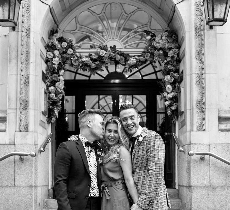 Grooms stand with wedding guest on their wedding day