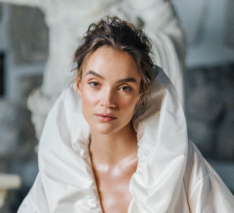 Bride with glowy natural makeup and messy updo with puff wedding dress