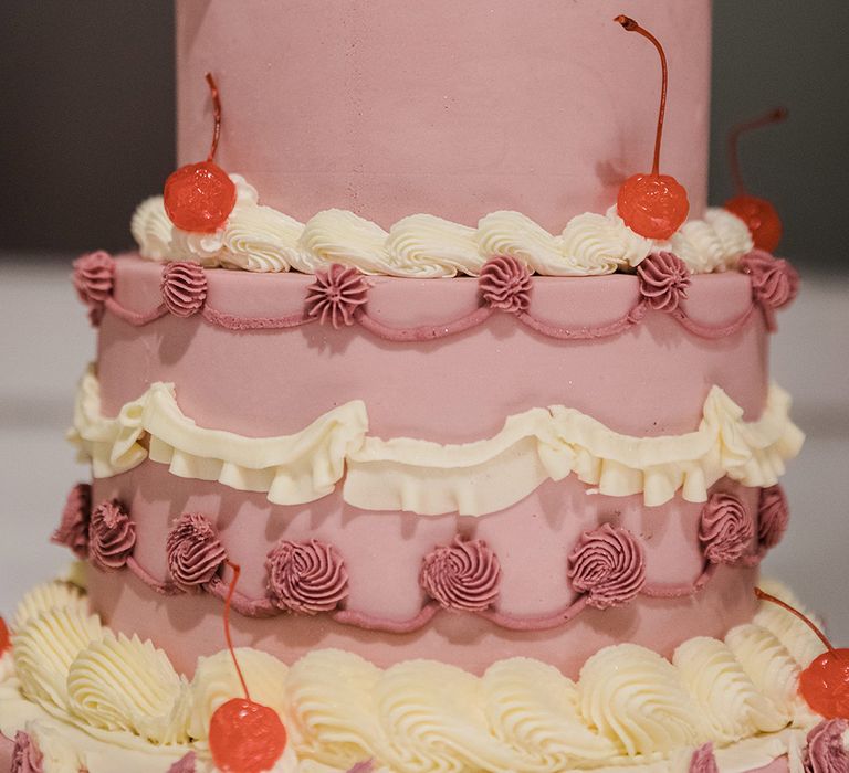 Close up of the three tier purple and white wedding cake with decorative icing and cherries