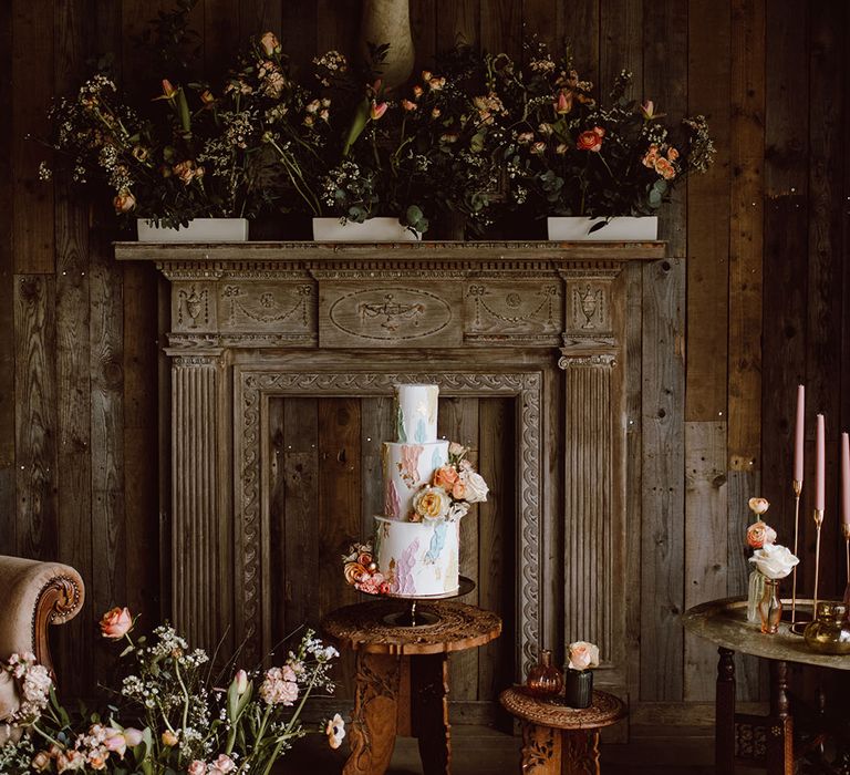 Three-tier white buttercream wedding cake with pastel pink, yellow, green and blue and lilac design at Montague Farm Hankham