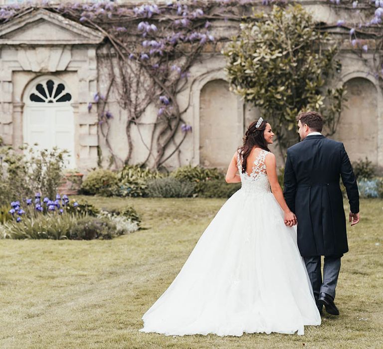 Bride and groom walk together in the gardens of Kirtlington Park House wedding venue 