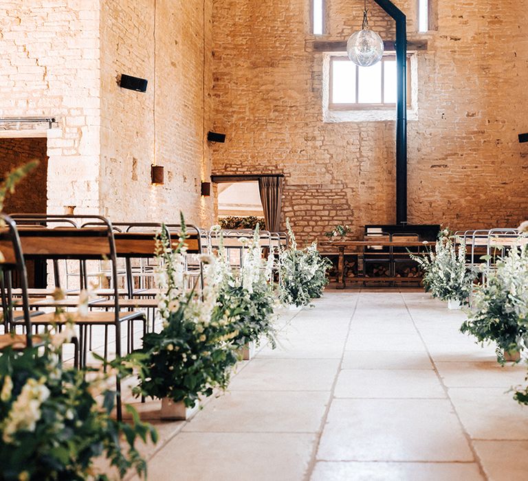 White flowers with foliage aisle decoration at rustic wedding venue with disco ball decor 