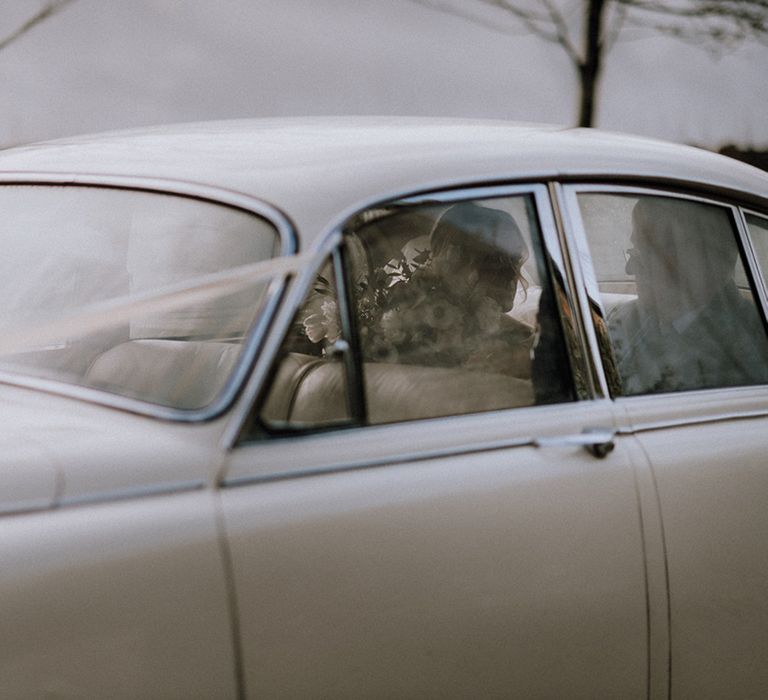 Bride and the father of the bride sit in their white wedding car transport 