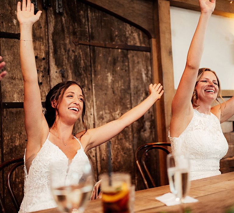 Brides raise their hands and arms together in celebration