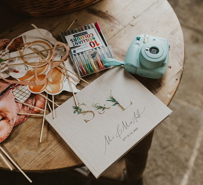 Personalised wedding guest book with coloured pens, a polaroid camera and props 