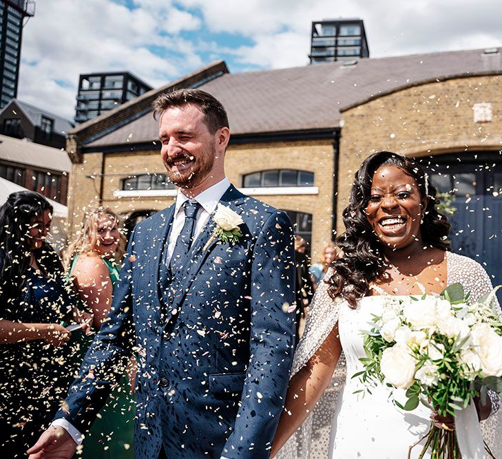 Bride & groom walk through confetti at Trinity Buoy Wharf after wedding ceremony 