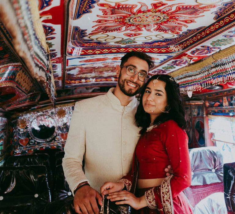 Bride & groom stand in colourful Pakistani wedding bus 