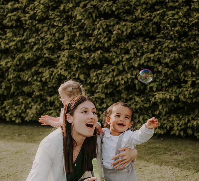 Wedding guest and baby play with bubbles in the outdoors 