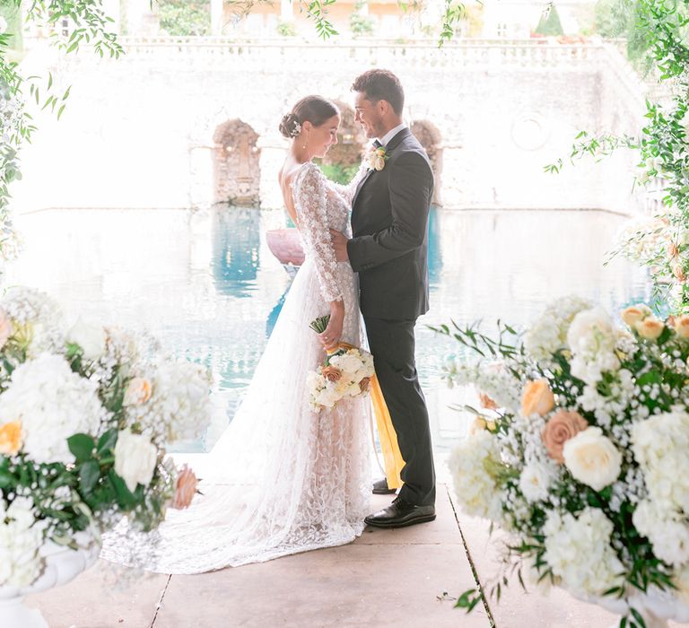 The couple laughs together on their traditional and classic wedding day with the groom in black tie and the bride in a lace wedding dress