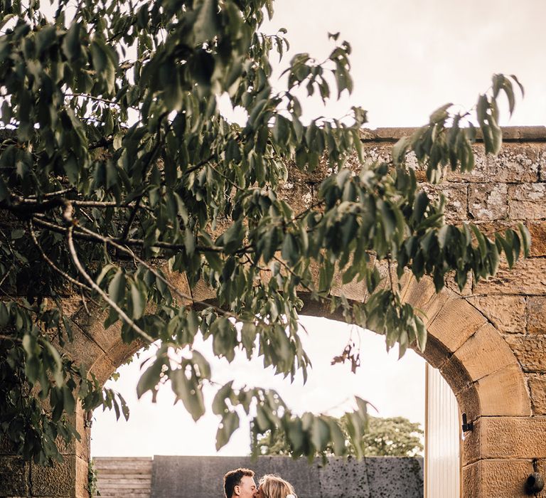 Bride & groom kiss in doorway outdoors in Scotland 