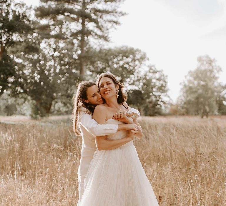 The brides share an intimate embrace in a field for their wedding at the Wilderness Reserve 