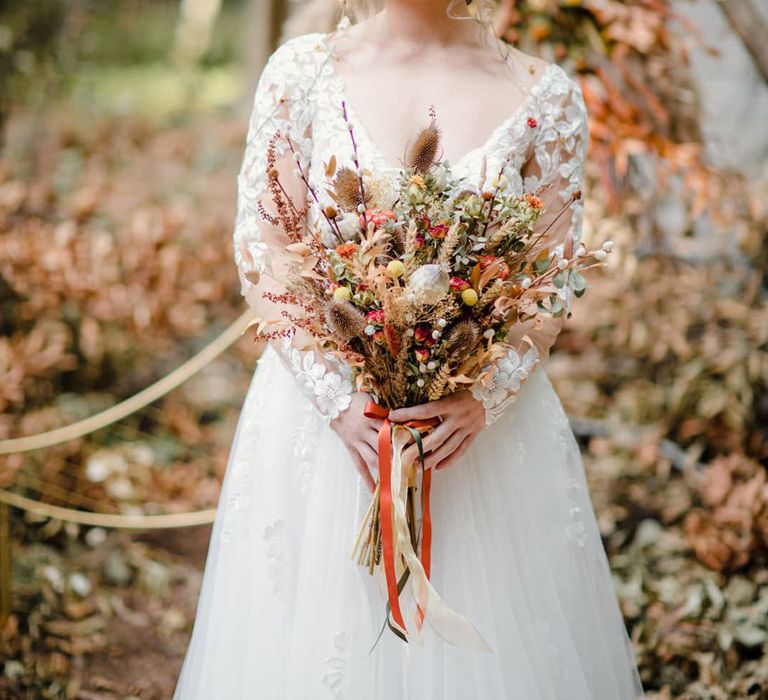 Bride in long sleeved v neck soft ivory dress with lace floral detailing on the bodice and sheer sleeves