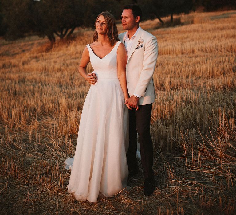 Bride & groom stand outdoors for couples portraits during golden hour