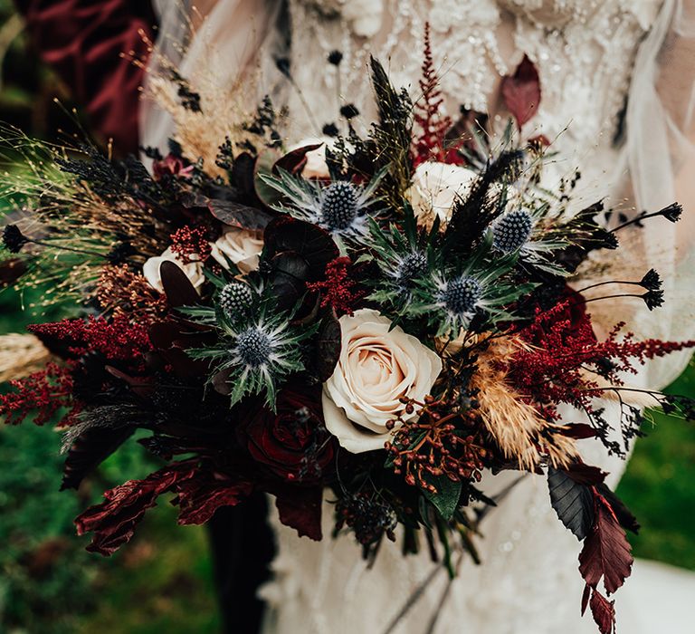 Cream roses, thistle, and autumn leaves make up the autumnal gothic bridal bouquet 