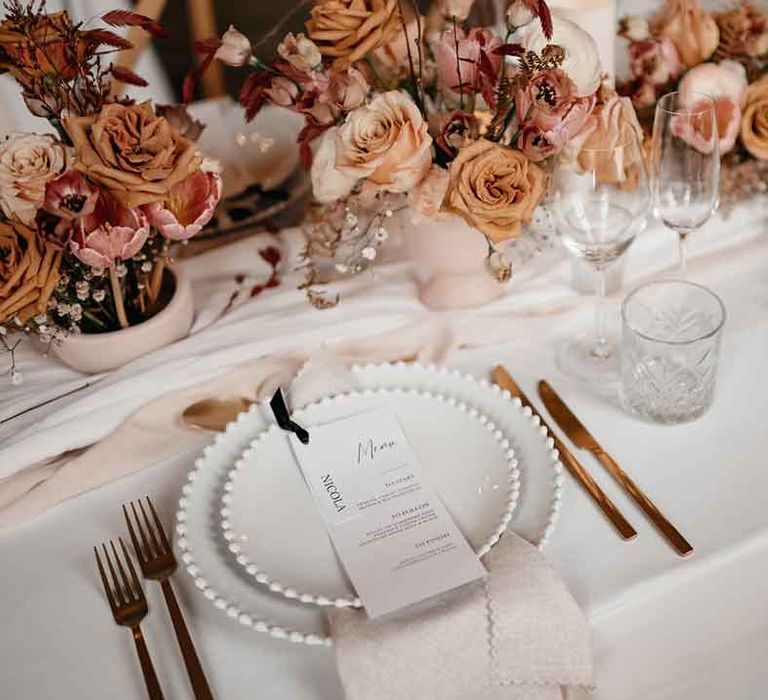 Rustic luxe wedding tablescape with toffee, nude and blush colour palette, soft linen table runners, dried pink garden roses, gold cutlery and charger plates 