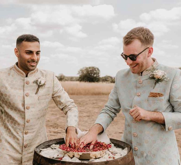 Groom in mint green Indian Sherwani with white garden rose and foliage boutonniere and grooms sunglasses partaking in Indian wedding tradition with groom in cream and gold Indian sherwani and white garden rose boutonniere 