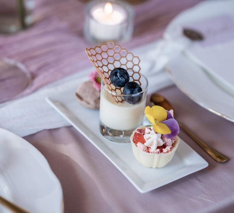 Trio of mini wedding desserts on rectangular plate on lavender tablecloth with lilac tulle table runner