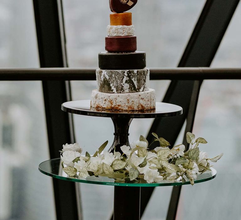 Seven layer wedding cheese tower on wooden cake stand with white rose and foliage decorations at The Gherkin 