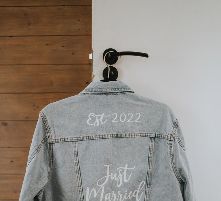 Beach wedding at Watermouth Cove with the bride's light blue denim jacket hanging up with 'Just Married' slogan and wedding year 